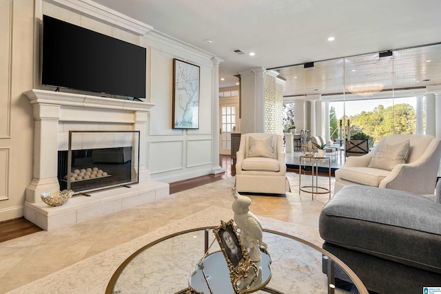 living room featuring crown molding, decorative columns, light hardwood / wood-style floors, and a fireplace