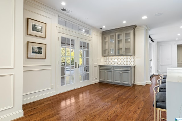 bar featuring french doors, decorative backsplash, dark hardwood / wood-style floors, crown molding, and gray cabinets