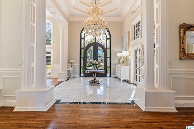 foyer featuring a towering ceiling, crown molding, hardwood / wood-style floors, and french doors