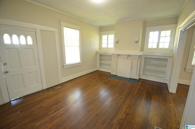 foyer with crown molding, a wealth of natural light, a fireplace, and dark hardwood / wood-style flooring