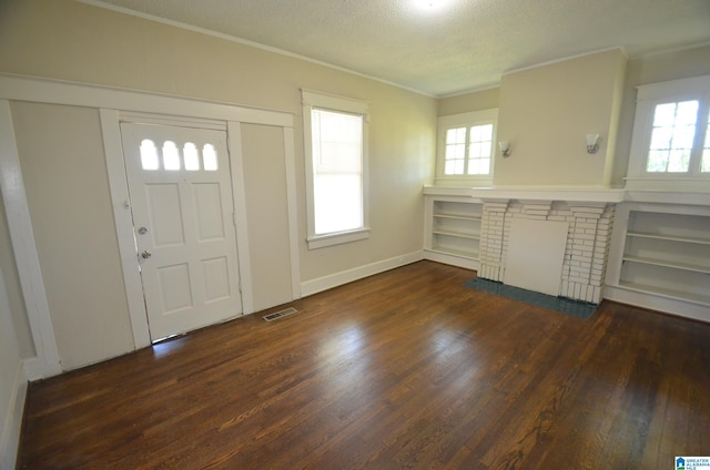 entrance foyer with ornamental molding, a textured ceiling, dark wood-type flooring, and a brick fireplace