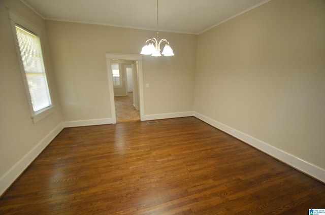 spare room featuring crown molding, an inviting chandelier, and dark hardwood / wood-style floors