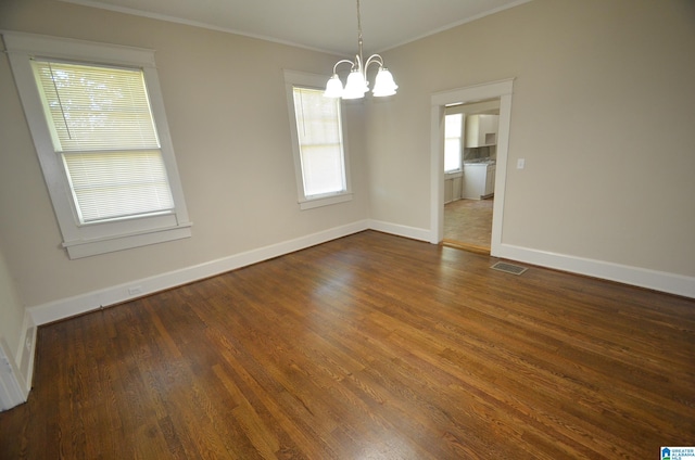 spare room with ornamental molding, dark hardwood / wood-style floors, and a chandelier