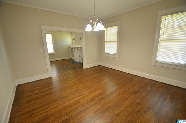 unfurnished dining area with an inviting chandelier, ornamental molding, and dark hardwood / wood-style flooring