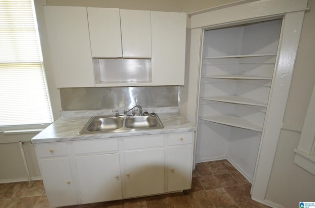 kitchen featuring decorative backsplash, white cabinets, and sink