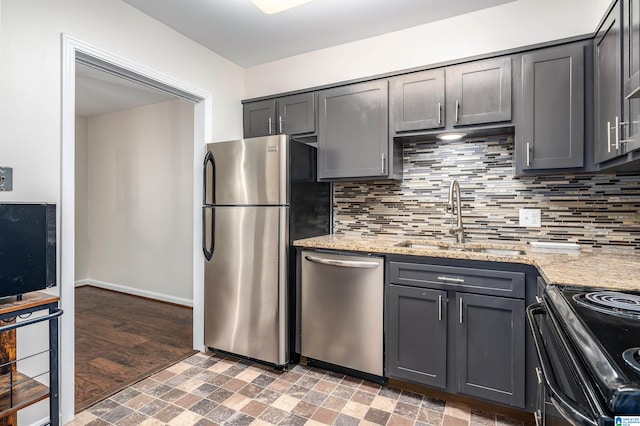 kitchen with stainless steel appliances, light stone countertops, sink, and dark hardwood / wood-style flooring