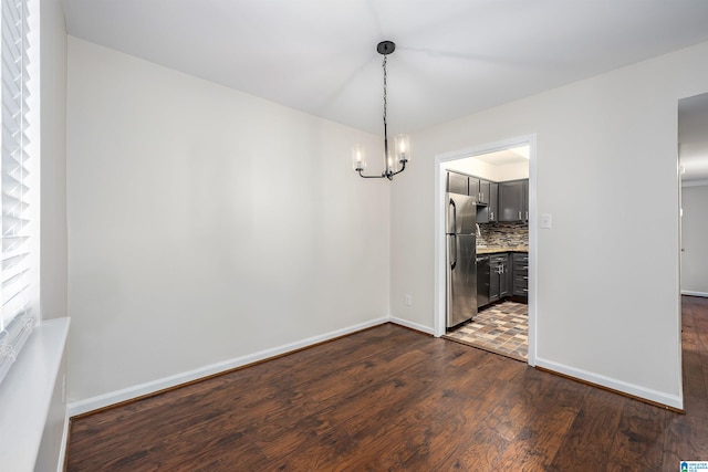 unfurnished dining area with a chandelier and dark wood-type flooring