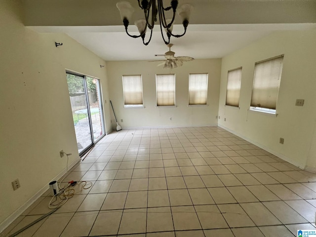 empty room with light tile patterned flooring and ceiling fan with notable chandelier