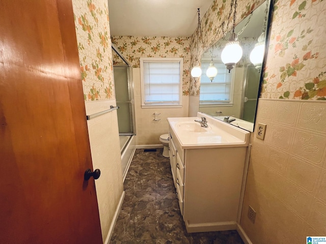 full bathroom featuring vanity, toilet, and shower / bath combination with glass door