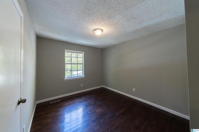 spare room with dark wood-type flooring and a textured ceiling