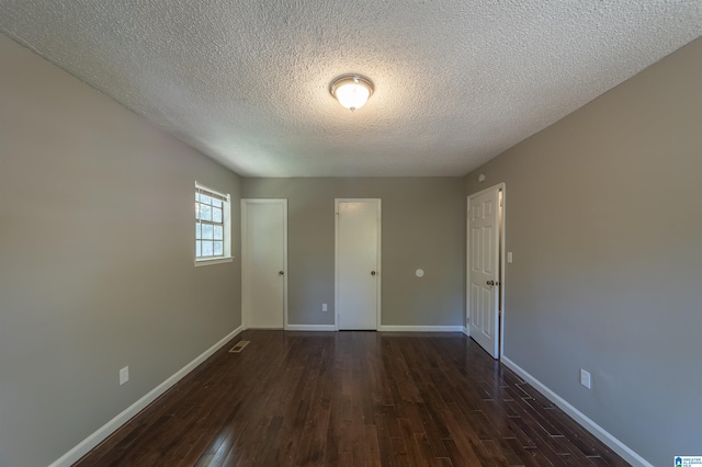 unfurnished bedroom with dark hardwood / wood-style floors and a textured ceiling