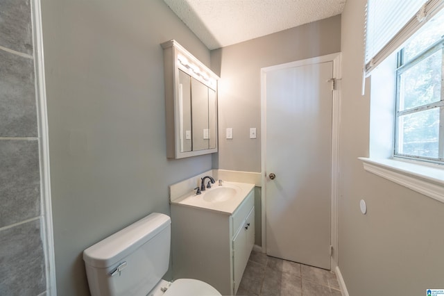 bathroom with toilet, a textured ceiling, vanity, and tile patterned flooring