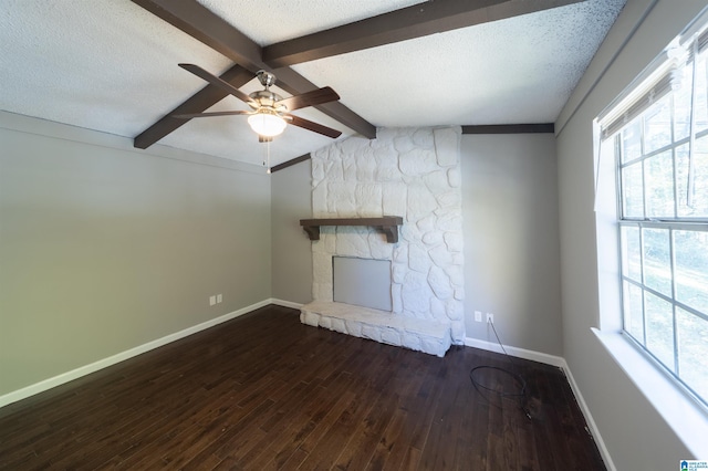 unfurnished living room with vaulted ceiling with beams, a fireplace, a textured ceiling, dark hardwood / wood-style flooring, and ceiling fan