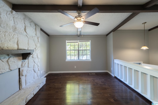 unfurnished living room with ceiling fan, a textured ceiling, beamed ceiling, and dark hardwood / wood-style flooring