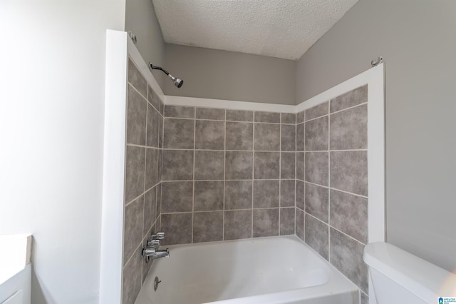 full bathroom featuring vanity, toilet, a textured ceiling, and tiled shower / bath