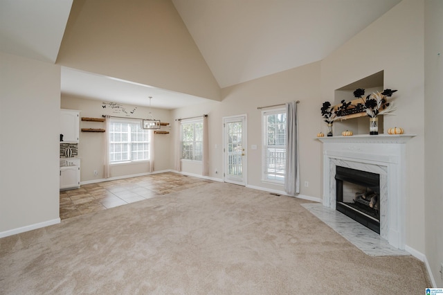 unfurnished living room featuring a premium fireplace, light colored carpet, and high vaulted ceiling