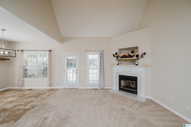 unfurnished living room featuring a chandelier, vaulted ceiling, light carpet, and a fireplace