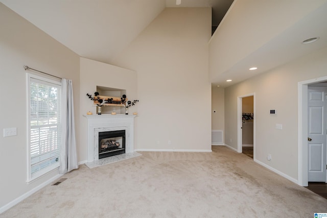 unfurnished living room featuring a premium fireplace, light colored carpet, and high vaulted ceiling