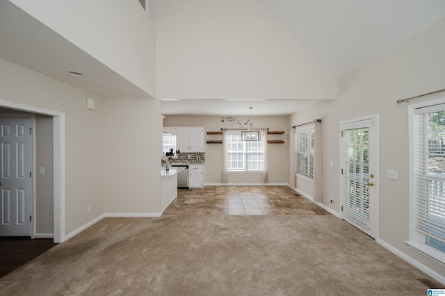 unfurnished living room featuring a wealth of natural light, a barn door, and light colored carpet