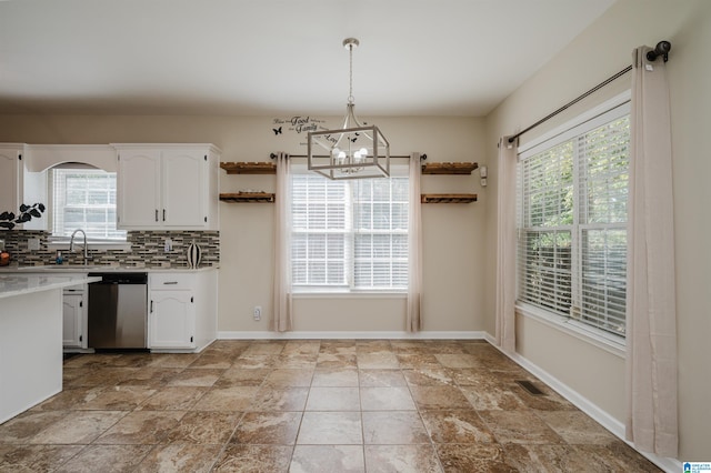 kitchen with white cabinetry, stainless steel dishwasher, hanging light fixtures, and backsplash