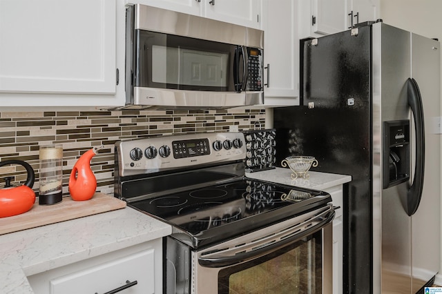 kitchen with backsplash, stainless steel appliances, and white cabinets