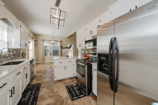 kitchen featuring kitchen peninsula, sink, decorative light fixtures, appliances with stainless steel finishes, and tasteful backsplash