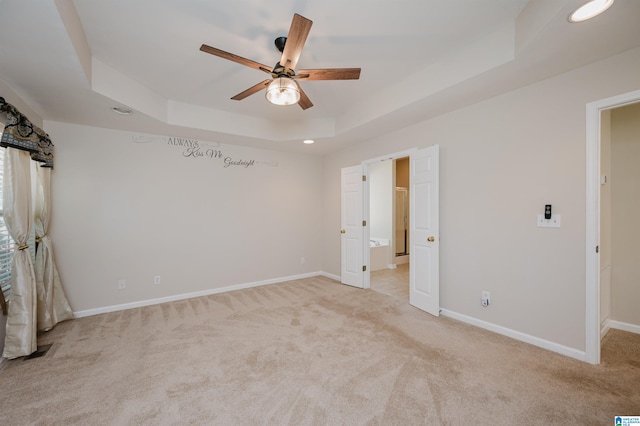 carpeted empty room with ceiling fan and a raised ceiling