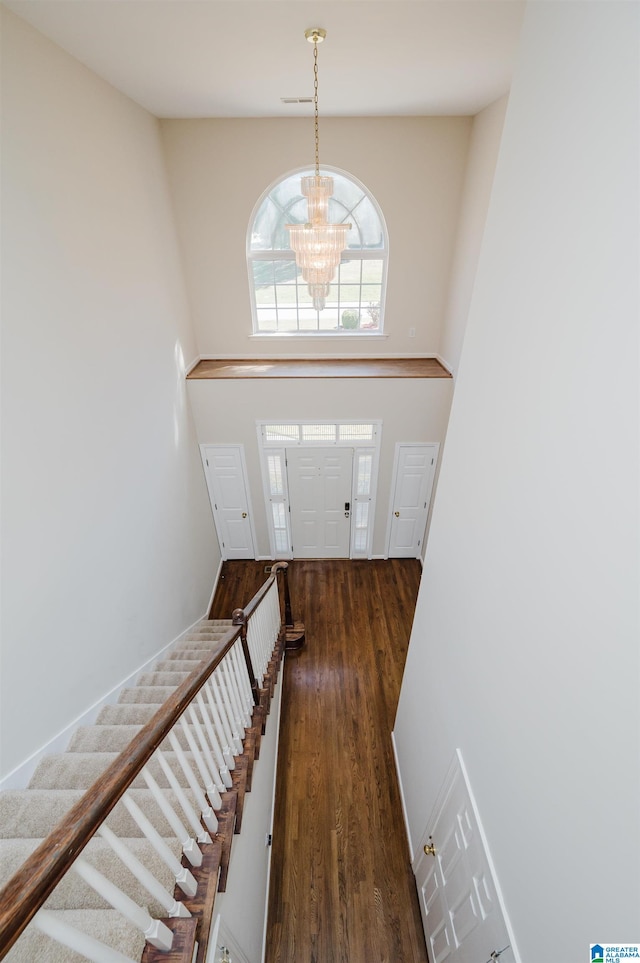 entrance foyer with a high ceiling, dark hardwood / wood-style floors, and an inviting chandelier