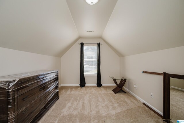 bonus room with vaulted ceiling and light carpet