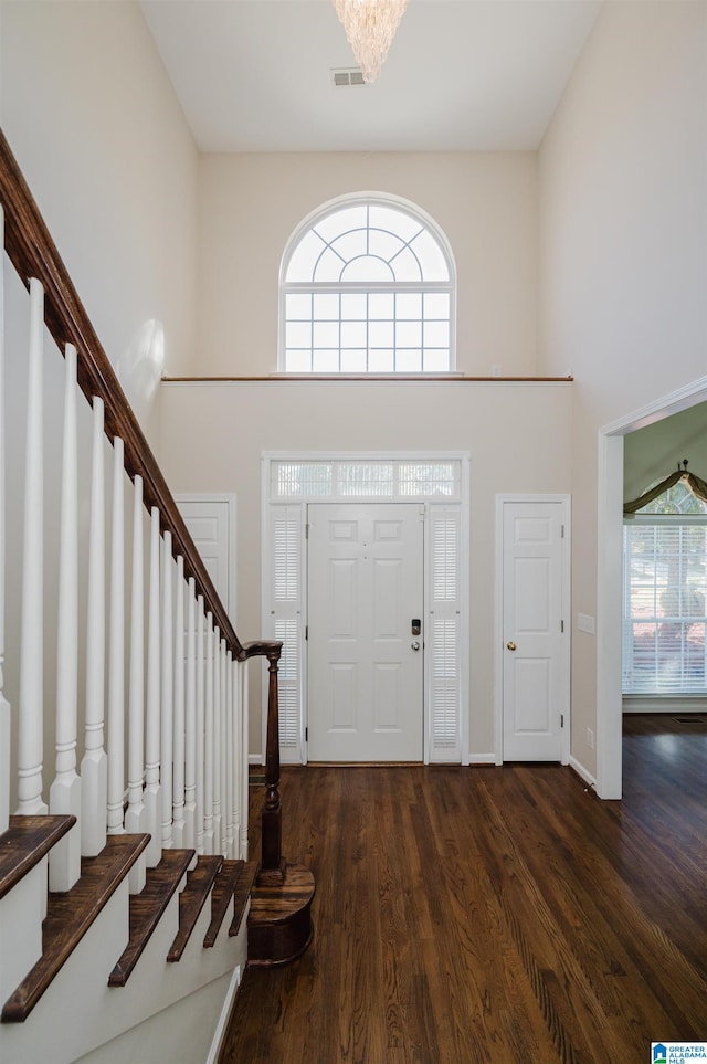 foyer featuring a high ceiling, a notable chandelier, dark hardwood / wood-style floors, and a healthy amount of sunlight