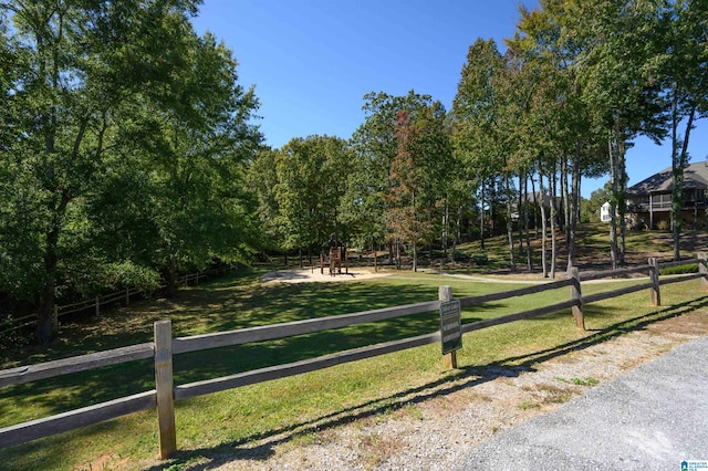 view of community with a lawn, a playground, and a rural view