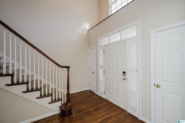 entrance foyer featuring dark wood-type flooring and a towering ceiling