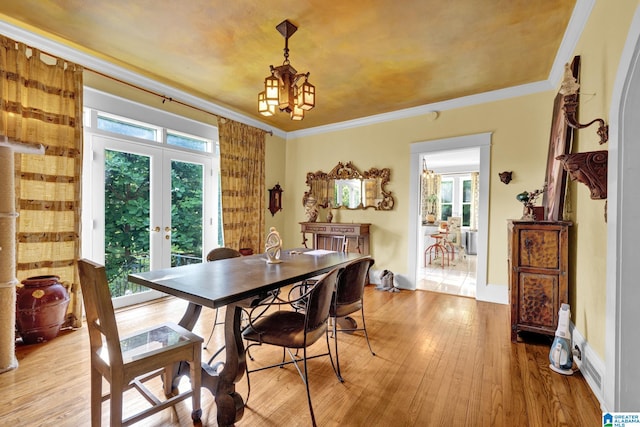 dining space featuring ornamental molding, french doors, light hardwood / wood-style flooring, and a healthy amount of sunlight