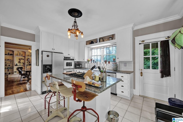 kitchen with dark stone countertops, appliances with stainless steel finishes, light tile patterned floors, and white cabinets