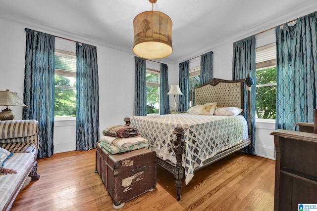 bedroom with crown molding and light hardwood / wood-style flooring