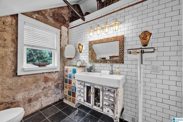 bathroom with tile walls, sink, vaulted ceiling, and toilet