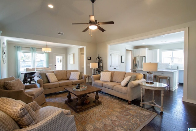 living room with dark wood-type flooring, ceiling fan, vaulted ceiling, and plenty of natural light