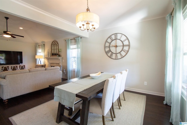 dining space featuring dark wood-type flooring, crown molding, lofted ceiling, and ceiling fan with notable chandelier