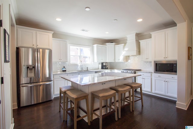 kitchen with a kitchen island, dark wood-type flooring, custom range hood, white cabinets, and appliances with stainless steel finishes