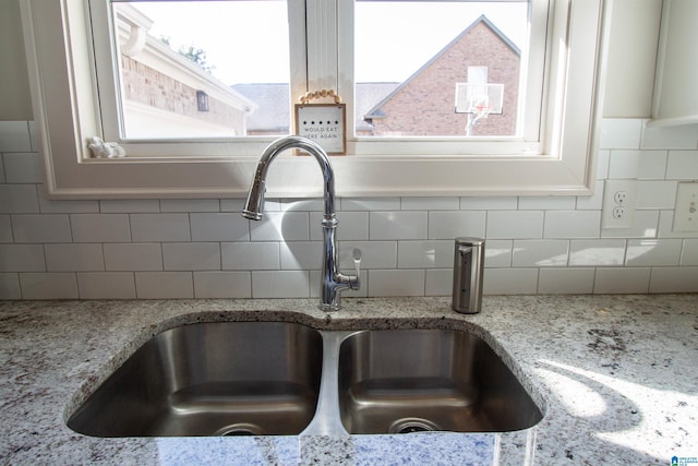 interior details featuring sink, light stone countertops, and decorative backsplash