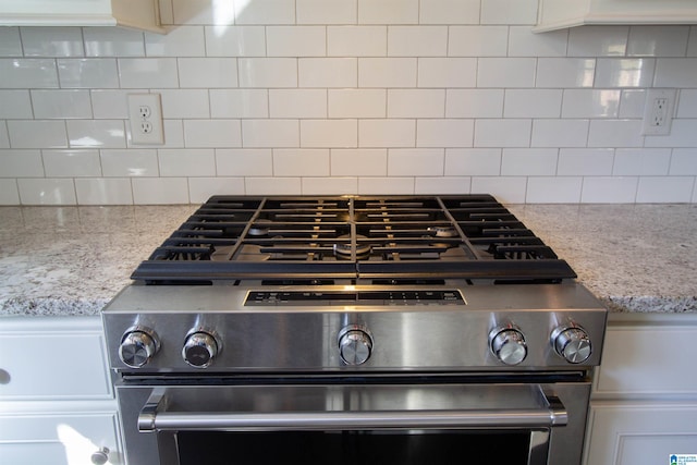 room details featuring decorative backsplash, high end range, and light stone counters