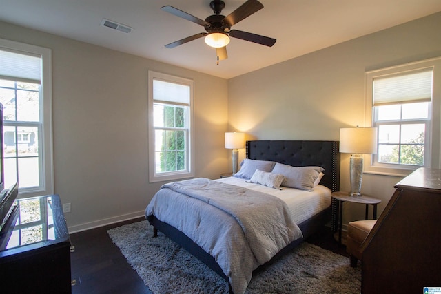 bedroom featuring multiple windows, dark hardwood / wood-style floors, and ceiling fan