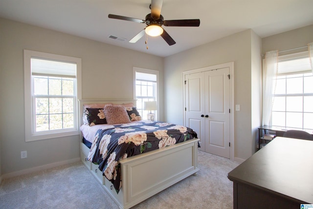 carpeted bedroom with multiple windows, a closet, and ceiling fan