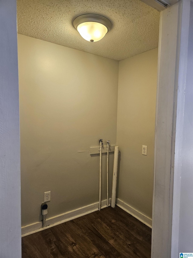 clothes washing area featuring dark hardwood / wood-style flooring and a textured ceiling