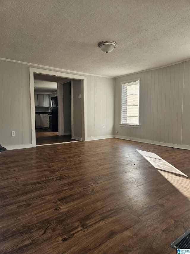 empty room featuring a textured ceiling, dark hardwood / wood-style floors, and wood walls