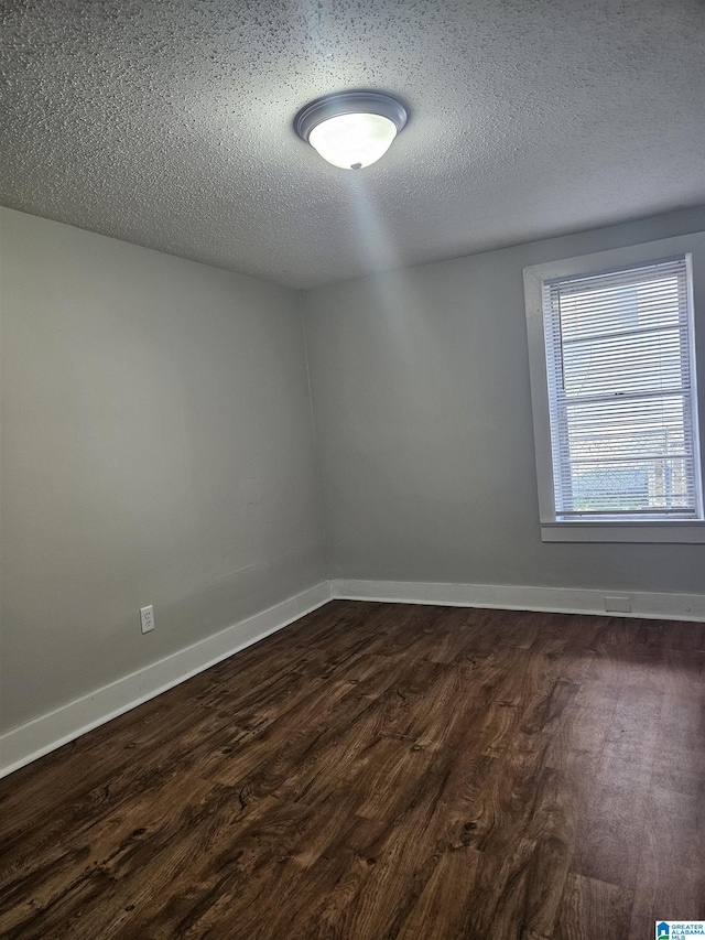 spare room with a textured ceiling and dark hardwood / wood-style floors