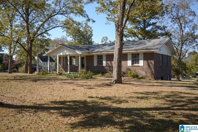 single story home featuring covered porch, brick siding, and a front yard