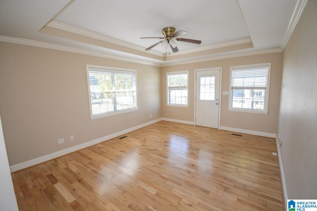 spare room featuring crown molding, ceiling fan, a raised ceiling, light wood-type flooring, and visible vents