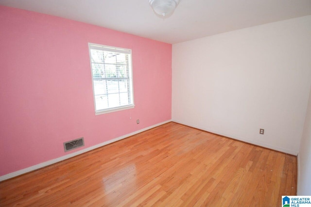 spare room featuring baseboards, wood finished floors, and visible vents