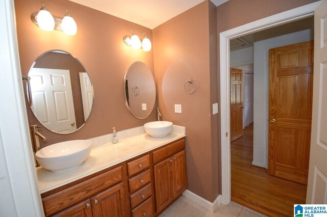 bathroom featuring a sink, baseboards, tile patterned flooring, and double vanity